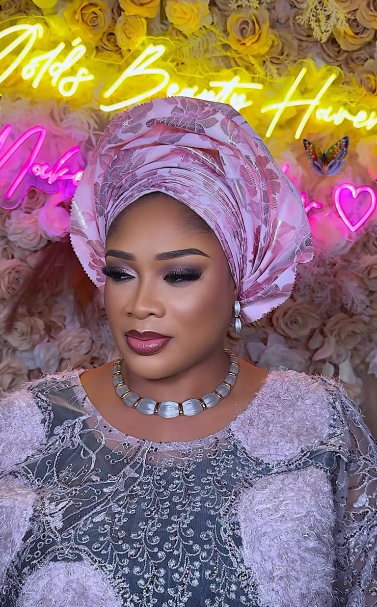 Traditional bridal makeup with pink gele and lace asoebi
